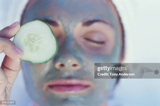 woman wearing facial mask, putting cucumber slice on eye, close-up - cucumber eye mask stock pictures, royalty-free photos & images