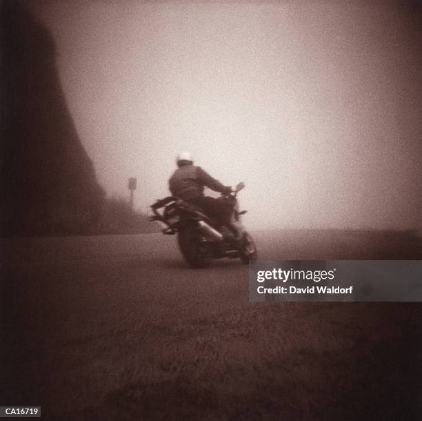 man riding motorcycle on curving road (soft focus, toned b&w) - waldorf fotografías e imágenes de stock