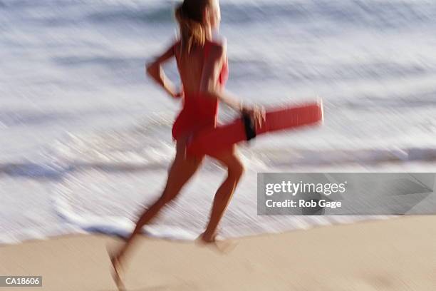 young female lifeguard running on beach, rear view (blurred motion) - beach lifeguard bildbanksfoton och bilder