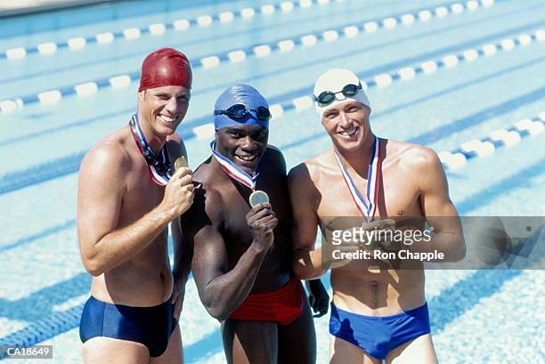 three male swimmers standing at poolside with medals, portrait - young men in speedos 個照片及圖片檔