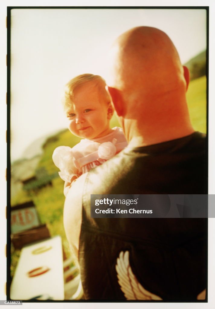 Father holding daughter (12-15 months), outdoors
