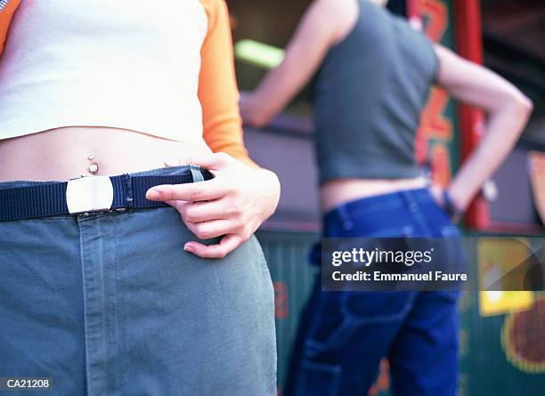 two teenage girls outdoors, one wearing navel jewelry, mid-section - piercing de umbigo - fotografias e filmes do acervo