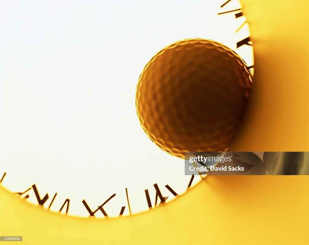 Golf ball on edge of hole, view from inside hole