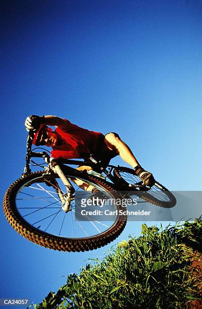 man riding mountain bike, mid-air, low angle view - carl stockfoto's en -beelden