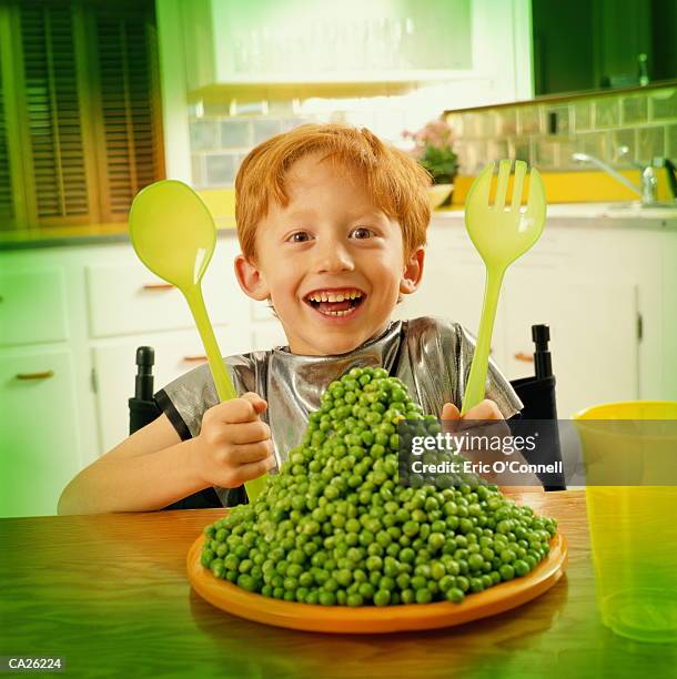 giant plate of peas in front of boy (7-9) at kitchen table, portrait - green pea stock pictures, royalty-free photos & images