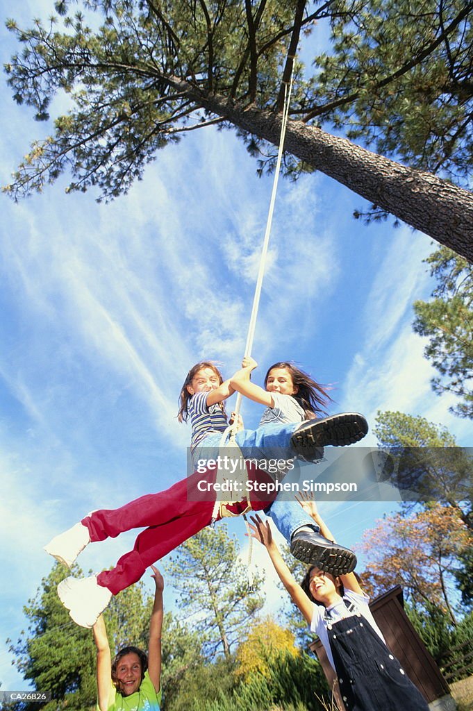 Two Hispanic American Girls Sharing Tree Swing High-Res Stock