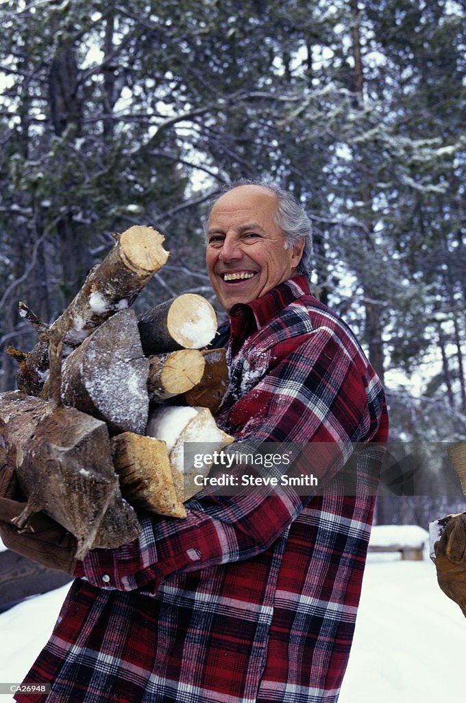 Mature man carrying firewood, winter, portrait