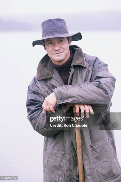 man wearing waterproofs on beach, leaning on stick, portrait - rain hat stock pictures, royalty-free photos & images