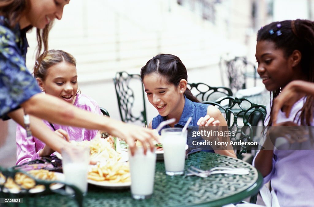 Girls (10-12) being served food in mall restaurant