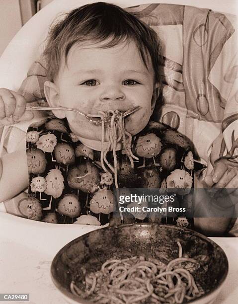 girl (12-15 months) eating spaghetti in high chair, portrait - super sensory stock pictures, royalty-free photos & images