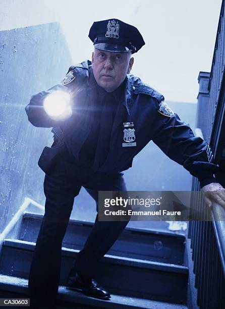 mature policeman shining torch, low angle view (gel effect) - police flashlight stock pictures, royalty-free photos & images