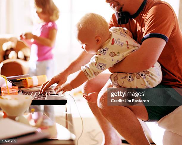 father holding baby (12-15 months) and working on laptop - 12 17 mois photos et images de collection
