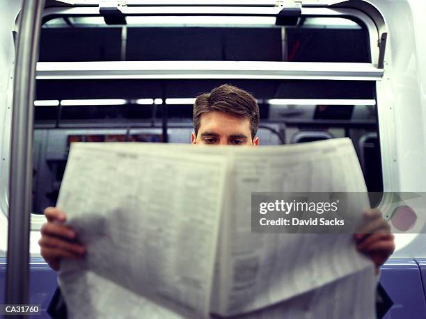 businessman reading newspaper in subway, close-up - zeitung im broadsheet format stock-fotos und bilder