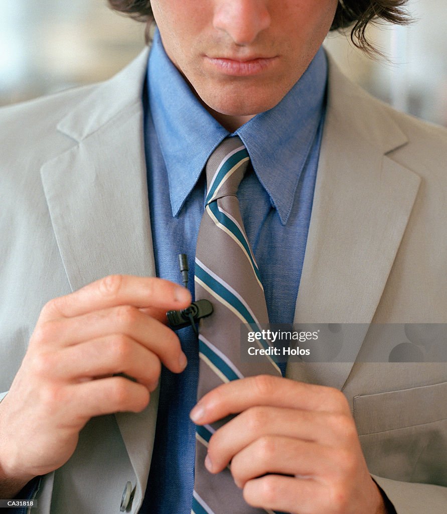 Businesssman clipping microphone to tie, close-up