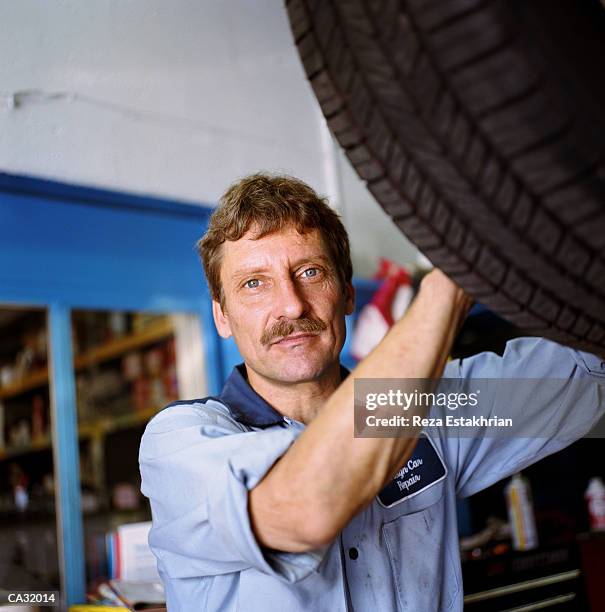 auto mechanic by car on lift, portrait - auto mechaniker stock-fotos und bilder