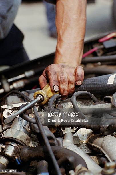 auto mechanic working on motor, close-up of hand holding screwdriver - auto mechaniker stock-fotos und bilder