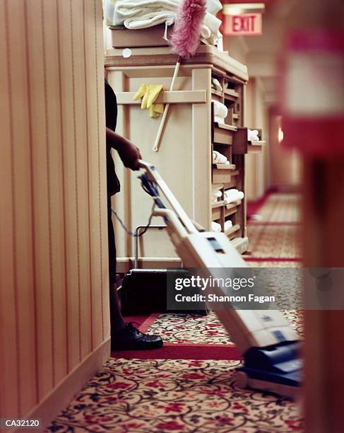 woman vacuuming carpet in hotel corridor - tâche fastidieuse photos et images de collection