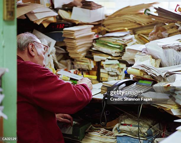 mature man in front of pile of papers - grote groep dingen stockfoto's en -beelden