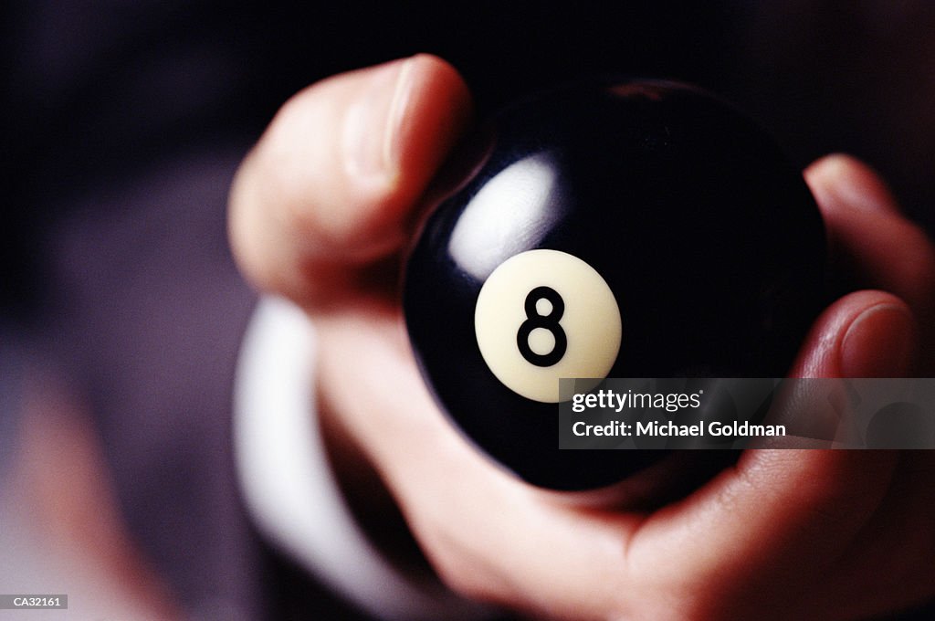 Man holding eight ball in hand, close-up
