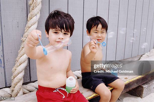 two boys (4-6) making bubbles at beach - michael virtue stock pictures, royalty-free photos & images