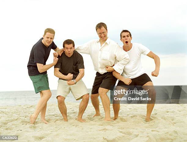 four young men flexing muscles on beach, portrait - muscle men at beach stock-fotos und bilder