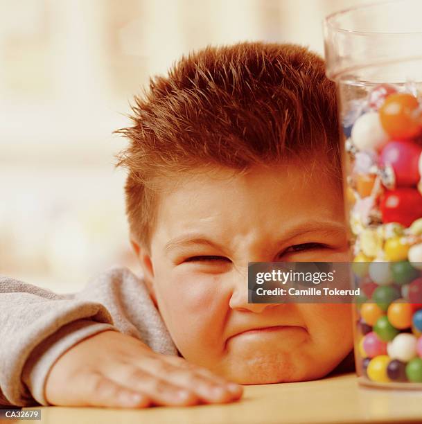 boy (4-6) making face near candy jar - candy jar stock pictures, royalty-free photos & images