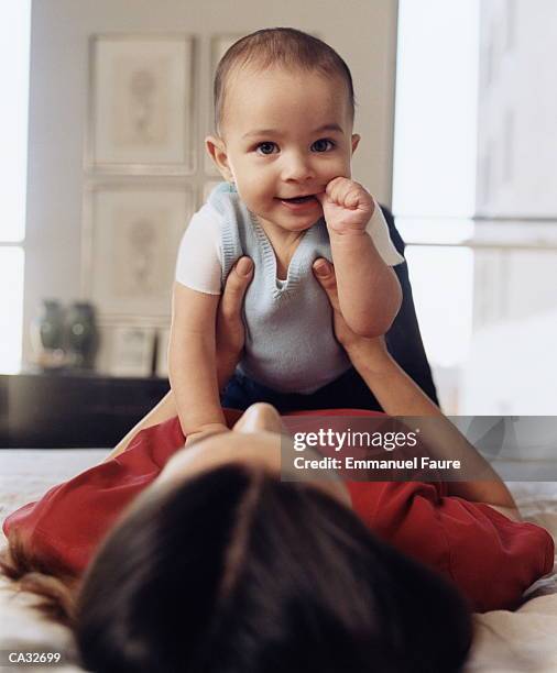 mother holding baby (6-9 months) with finger in mouth - emmanuel stock pictures, royalty-free photos & images