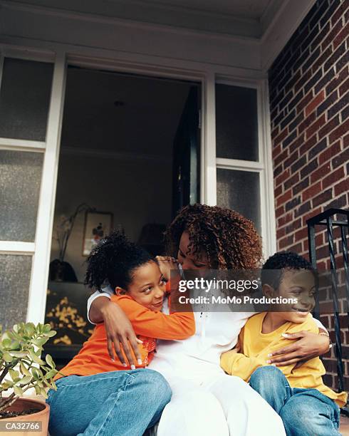 mother hugging son and daughter (5-7) in front of house - umbral fotografías e imágenes de stock