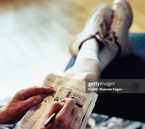 man doing crossword puzzle (focus on hands and puzzle) - taburete pequeño fotografías e imágenes de stock
