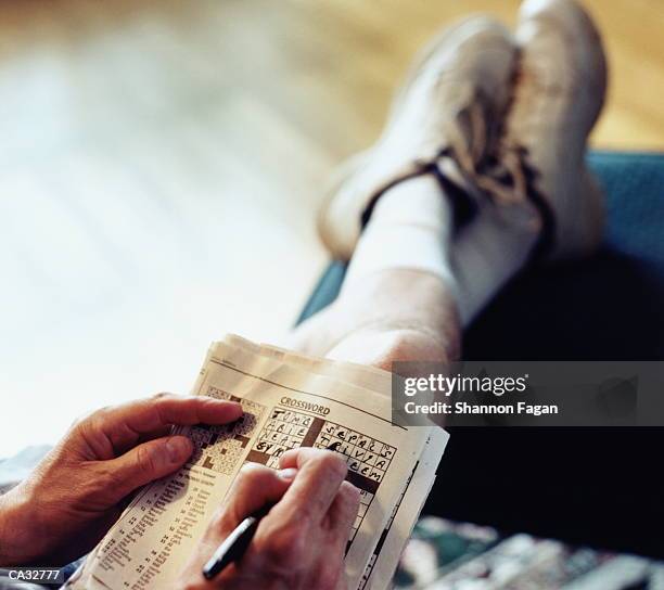 man doing crossword puzzle (focus on hands and puzzle) - crossword puzzle stock pictures, royalty-free photos & images