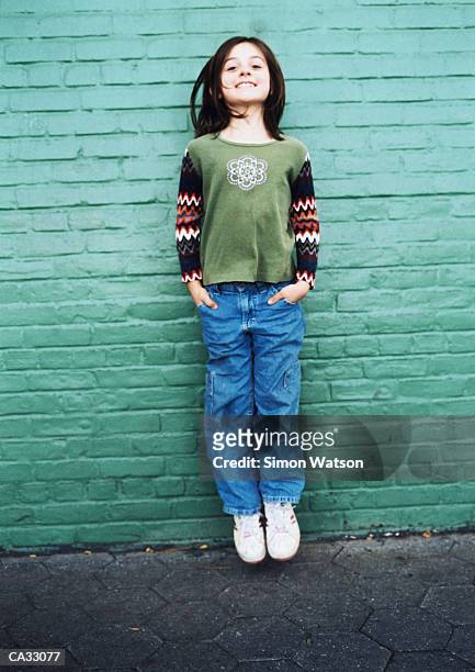 girl (8-10) jumping in front of brick wall on street - watson stock pictures, royalty-free photos & images