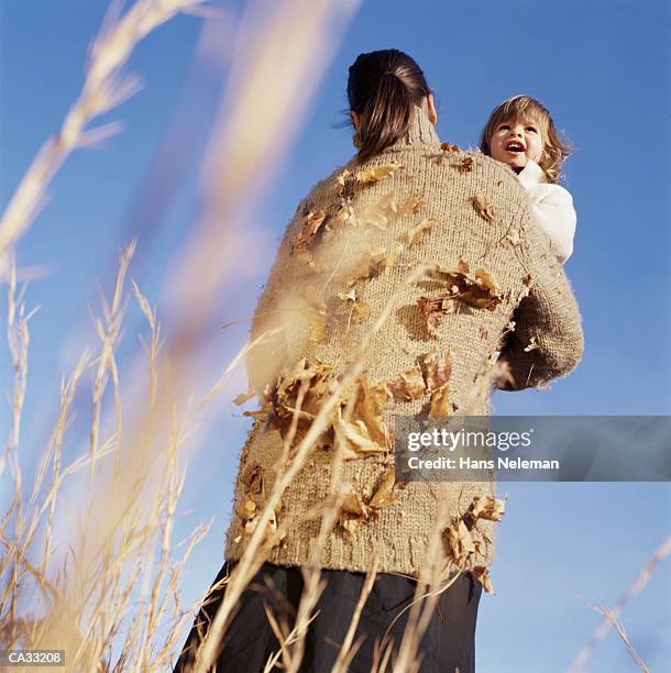 mother carrying girl (3-5) in field - hans neleman stockfoto's en -beelden