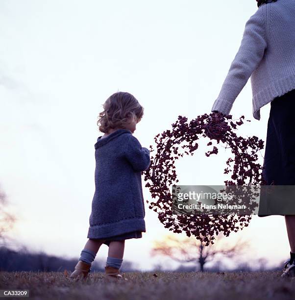 girl (3-5 ) looking at wreath in mother's hand - hans neleman stockfoto's en -beelden