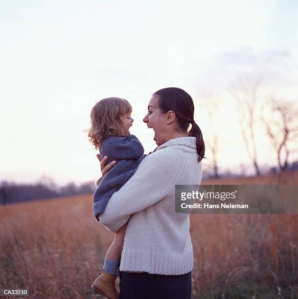 mother holding girl in field in winter - hans neleman 個照片及圖片檔