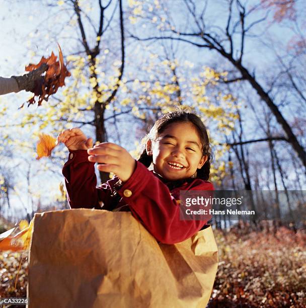 girl (6-8) playing in paper bag in autumn - hans neleman stockfoto's en -beelden
