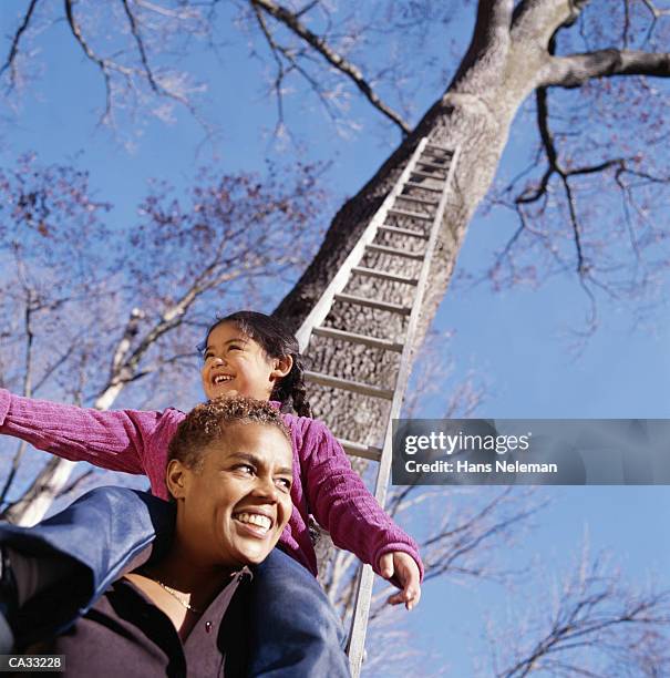 girl (6-8) sitting on mother's shoulders in autumn - hans neleman stockfoto's en -beelden