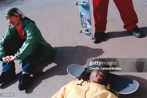 three teenage boys (15-17) relaxing with skateboards - leland bobbe foto e immagini stock