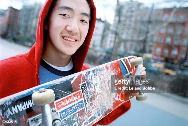 teenage boy (15-17) holding skateboard in city playground, portrait - leland bobbe foto e immagini stock