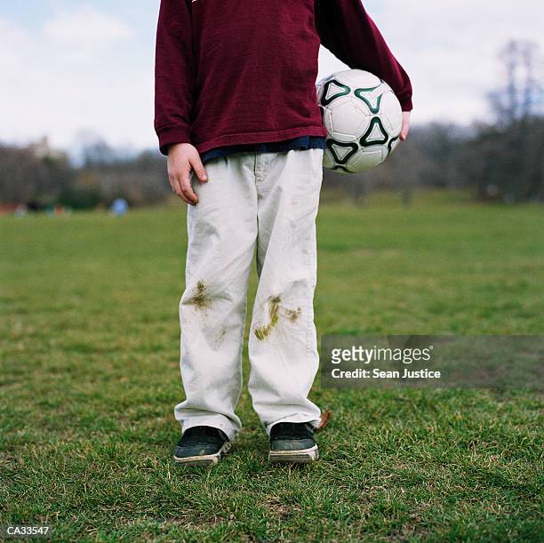 boy (7-9) holding soccer ball on field, low section - stained stock pictures, royalty-free photos & images