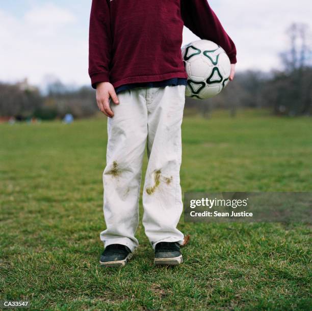 boy (7-9) holding soccer ball on field, low section - 褲 個照片及圖片檔