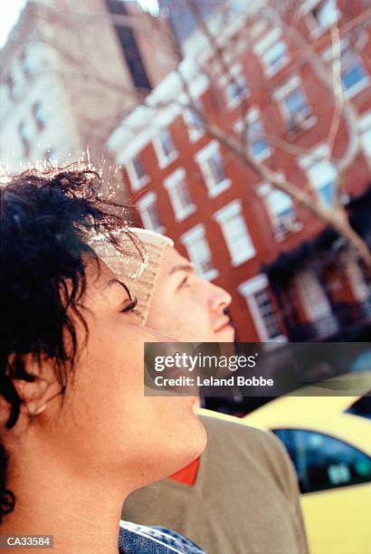 young couple looking upwards on city street, close-up - leland bobbe foto e immagini stock