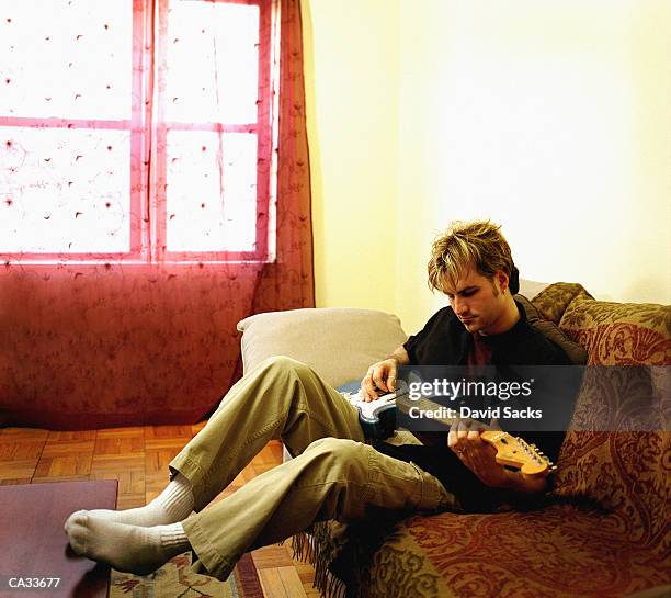 young man playing electric guitar at home - modern rock stock pictures, royalty-free photos & images
