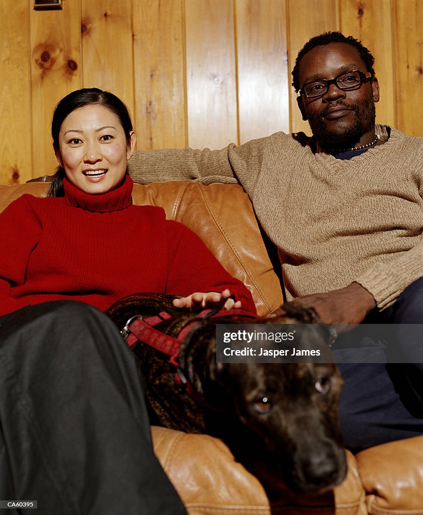 Couple on sofa with pit-bull terrier, portrait