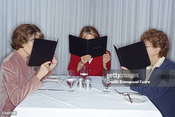 three mature women looking at menu in restaurant - menu stock pictures, royalty-free photos & images