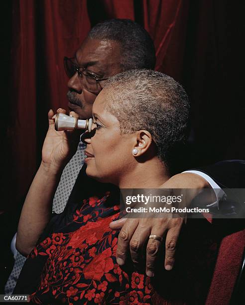 woman looking through opera glasses in theatre - binocolo da teatro foto e immagini stock