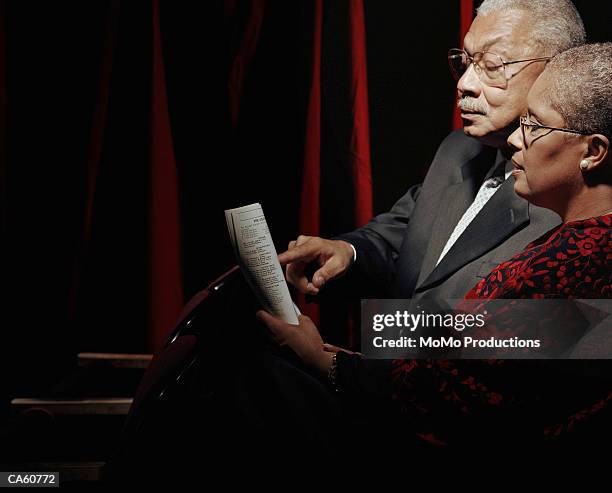 mature couple looking at program in opera house - abendgarderobe stock-fotos und bilder
