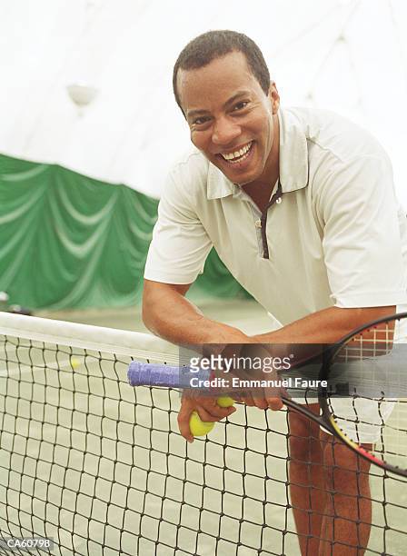 mature man on tennis court with raquet, smiling - emmanuel stock pictures, royalty-free photos & images