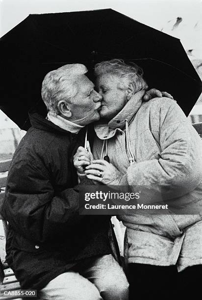 elderly couple kissing under umbrella, close-up (b&w) - rain kiss stock pictures, royalty-free photos & images