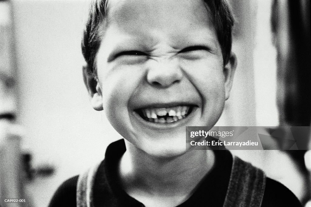 Boy (6-8) smiling, face creased into toothy grin, close-up (B&W)