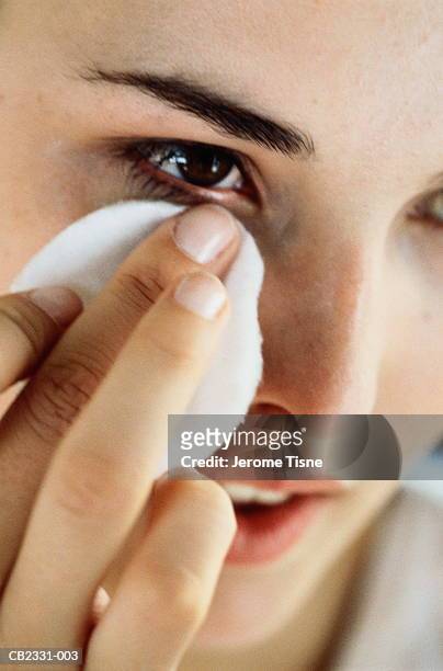 young woman removing make-up from eye area, close-up - démaquillant photos et images de collection